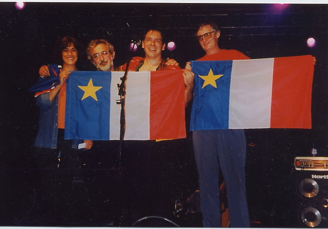 Patrice Boulliane remet le drapeau acadien à Annie Benoit, Maurice Segall et Albert Weber